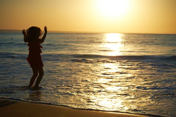 Девушка играет на пляже на закате — стоковое фото