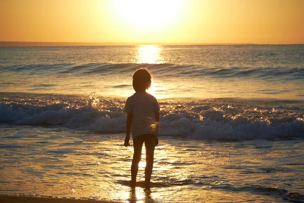 Boy playing on beach at sunset — Stock Photo, Image