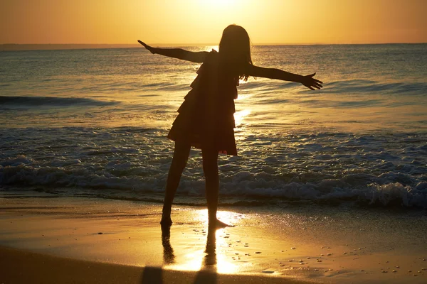 Girl playing on beach at sunset — Stock Photo, Image