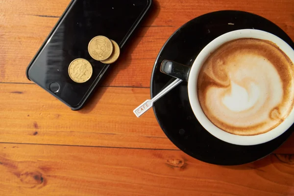 Taza de café, monedas y teléfono — Foto de Stock