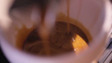 Closeup of coffee maker pouring coffee in white cup