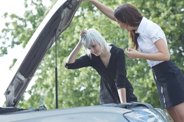 Молодые женщины возле сломанной машины — стоковое фото