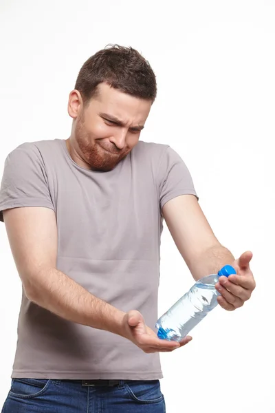 Jovem sorridente homem cuidadosamente considerar garrafa de água — Fotografia de Stock