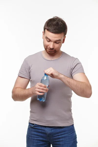 Young smiling man carefully consider water bottle — Stock Photo, Image