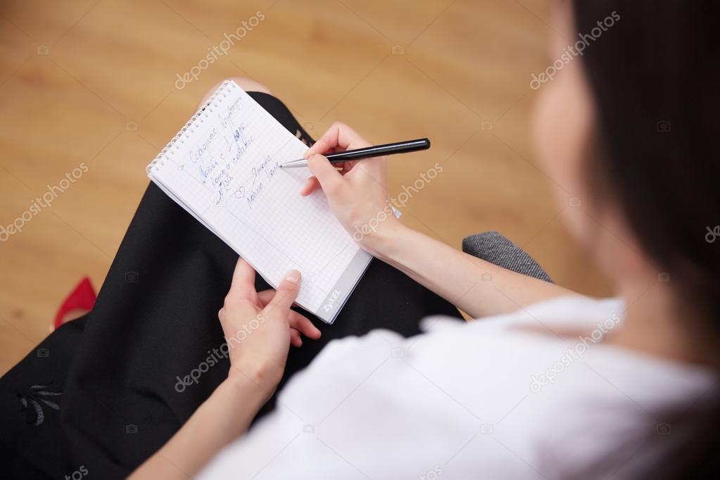 Businesswoman writing in notepad 