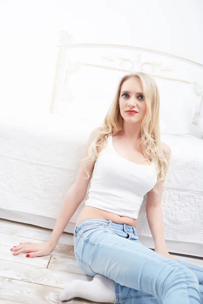 Blond kvinna sitter nära bed — Stockfoto