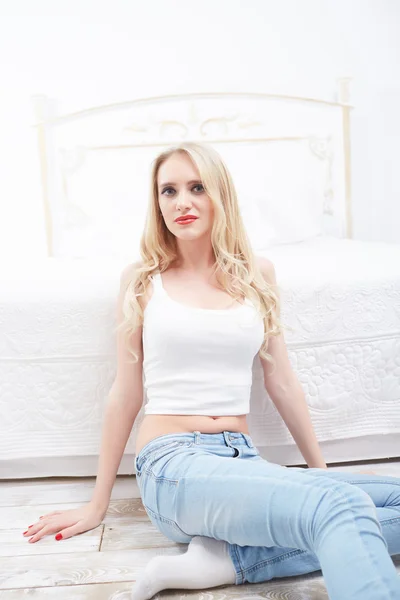 Blond kvinna sitter nära bed — Stockfoto