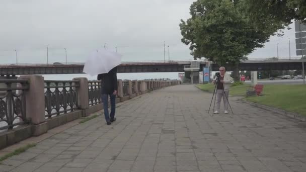 Kamera muž filmy senior model chůze na nábřeží řeky — Stock video