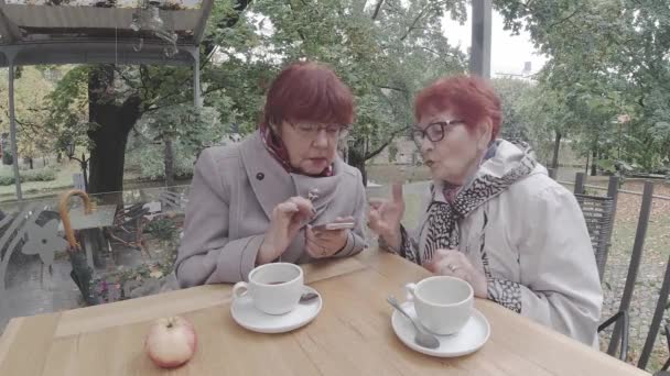 Pensionerade kvinnor i rockar tillbringar tid utomhus restaurang — Stockvideo