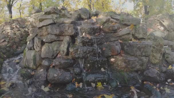 Water stroomt over bruine stenen van kunstmatige heuvel in het park — Stockvideo