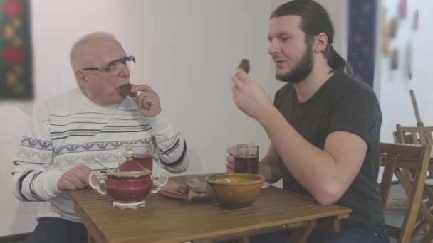 Velho e cara com barba passam o tempo bebendo chá no café — Vídeo de Stock