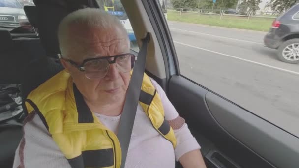유행하는 안경을 쓴 노련 한 은퇴 한 남자가 차를 운전하며 도로를 달리고 있다 — 비디오