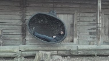 Keyifli, rahat adam müzede büyük siyah bir salıncakta yatıyor.