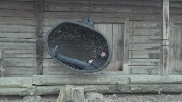 Délicieux gars détendu se trouve dans une grande balançoire noire dans le musée — Video