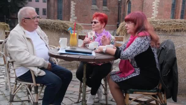Senior homme et les femmes parlent assis à une petite table avec des boissons — Video
