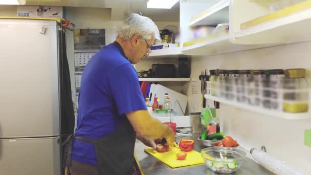 Gri saçlı petrol tankeri aşçısı akşam yemeği için salata hazırlar. — Stok video