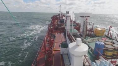 Kargo gemisi fırtınalı okyanusta yelken açar ve dalgalar gemiye çarpar.