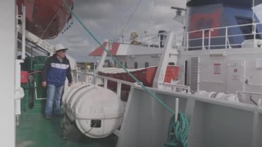 Kamera operatörü yeşil yük gemisi güvertesinde yürüyor