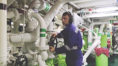 Motor tamircisi makine dairesinde duran siyah vanayı döndürür