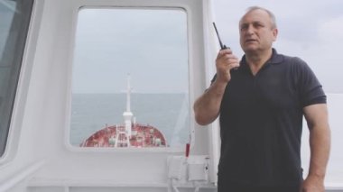 Siyah tişörtlü bir polis telsizden etrafa bakıyor.