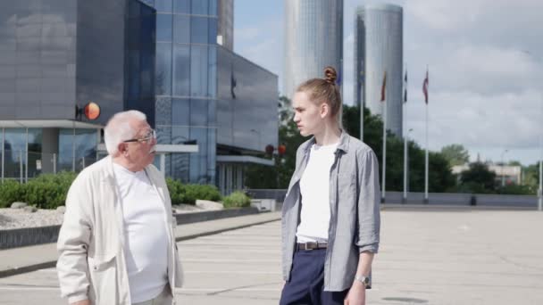 Guy interviewt gepensioneerde tegen multistory kantoorgebouw — Stockvideo