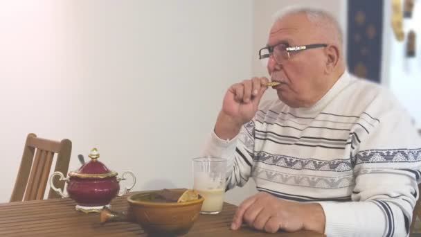 L'uomo in occhiali si siede e beve il latte con biscotti in caffè Video Stock