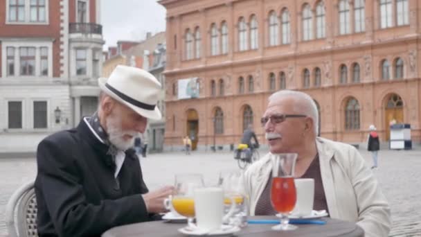 Starší muži sedí v městské kavárně a mluví proti budovám Royalty Free Stock Záběr