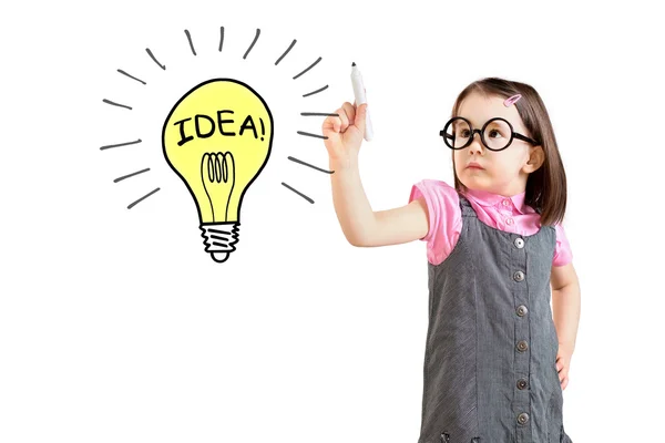 Cute little girl wearing business dress and drawing a light bulb. White background. — Stock Photo, Image