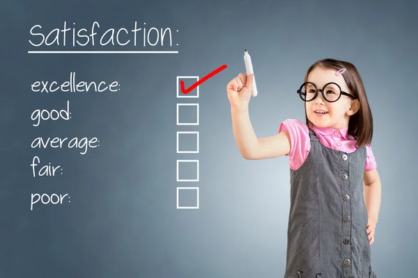 Linda niña con vestido de negocios y comprobar la excelencia en el formulario de encuesta de satisfacción del cliente. Fondo azul . —  Fotos de Stock