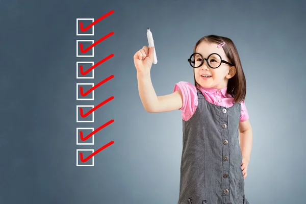 Söt liten flicka klädd i Business Dress och kontroll på checklisteboxar. Blå bakgrund. — Stockfoto