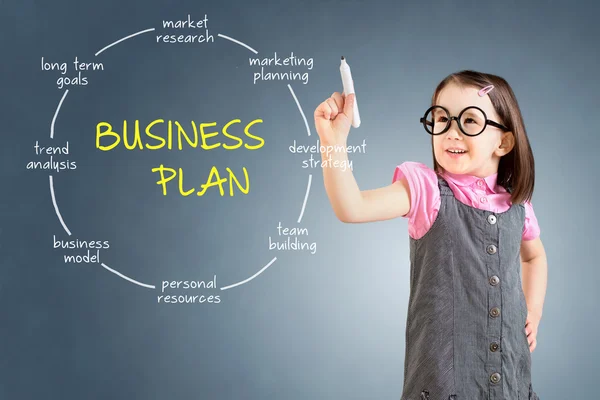 Schattig klein meisje dragen Business jurk en tekening business plan concept. Blauwe achtergrond. — Stockfoto