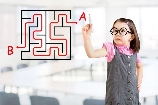 Nettes kleines Mädchen im Businesskleid und findet die Labyrinth-Lösung, die auf dem Whiteboard steht. Hintergrund Büro. — Stockfoto