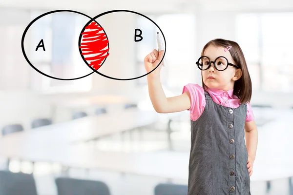 Petite fille mignonne portant une robe d'affaires et dessinant un diagramme de cercle intersecté sur un tableau blanc. Contexte du bureau . — Photo