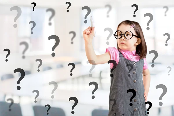 Söt liten flicka klädd i Business Dress och skriva frågetecken. Office-bakgrund. — Stockfoto