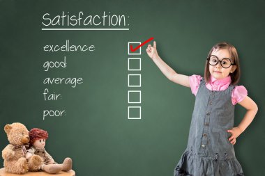 Sevimli küçük kız iş elbisesi giyen ve müşteri memnuniyeti anket formunda mükemmellik kontrol. Yeşil tebeşir panosunda gösteriliyor.