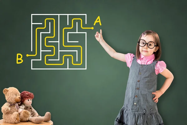 Nettes kleines Mädchen im Businesskleid und findet die Labyrinth-Lösung auf grünem Kreidebrett. — Stockfoto