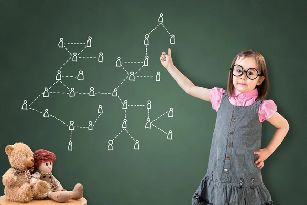可爱的小女孩穿着商务礼服，并在绿色粉笔板上展示社交网络概念. — 图库照片