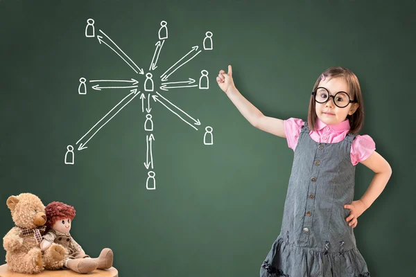 Linda niña con vestido de negocios y mostrando la estructura de la red social en el tablero de tiza verde . —  Fotos de Stock