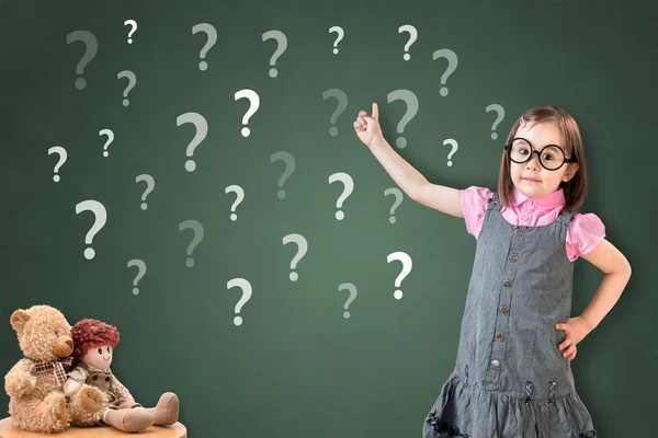 Petite fille mignonne portant une robe d'affaires et montrant un point d'interrogation sur le tableau de craie vert . — Photo