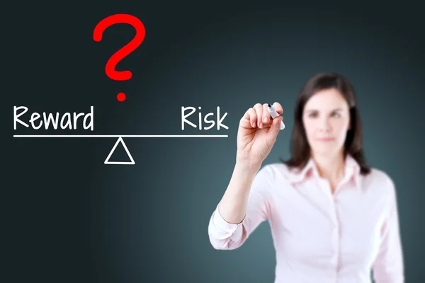 Young business woman writing question with risk compare to reward on balance bar. — Stock Photo, Image