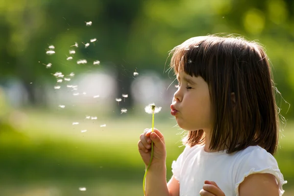 Piękne dziecko z kwiatem mniszka lekarskiego w parku wiosennym. Szczęśliwy dzieciak bawiący się na zewnątrz. — Zdjęcie stockowe