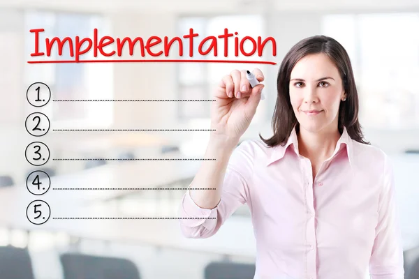Business woman writing blank Implementation list. Office background. — Stock Photo, Image