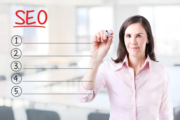 Business woman writing blank Seo (search engine optimization) list. Office background. — Stock Photo, Image