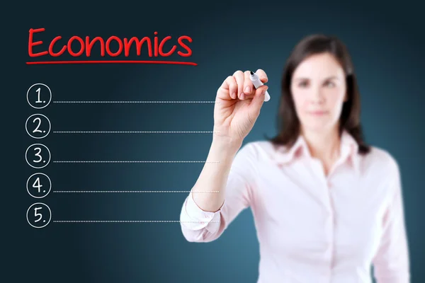 Business woman writing blank Economics list. Blue background. — Stock Photo, Image