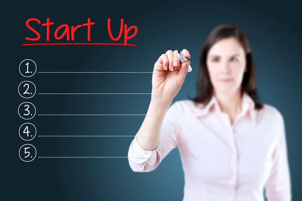 Mulher de negócios escrevendo lista Start-Up em branco. Fundo azul . — Fotografia de Stock