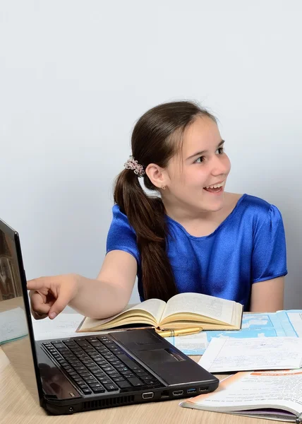 Vrolijke tiener schoolmeisje achter een bureau getraind met belangstelling op de computer. — Stockfoto