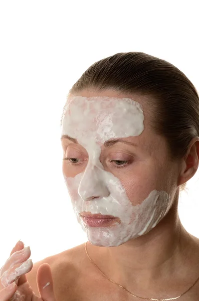 Donna infligge un cosmetico di maschera per la pelle del viso su sfondo bianco — Foto Stock