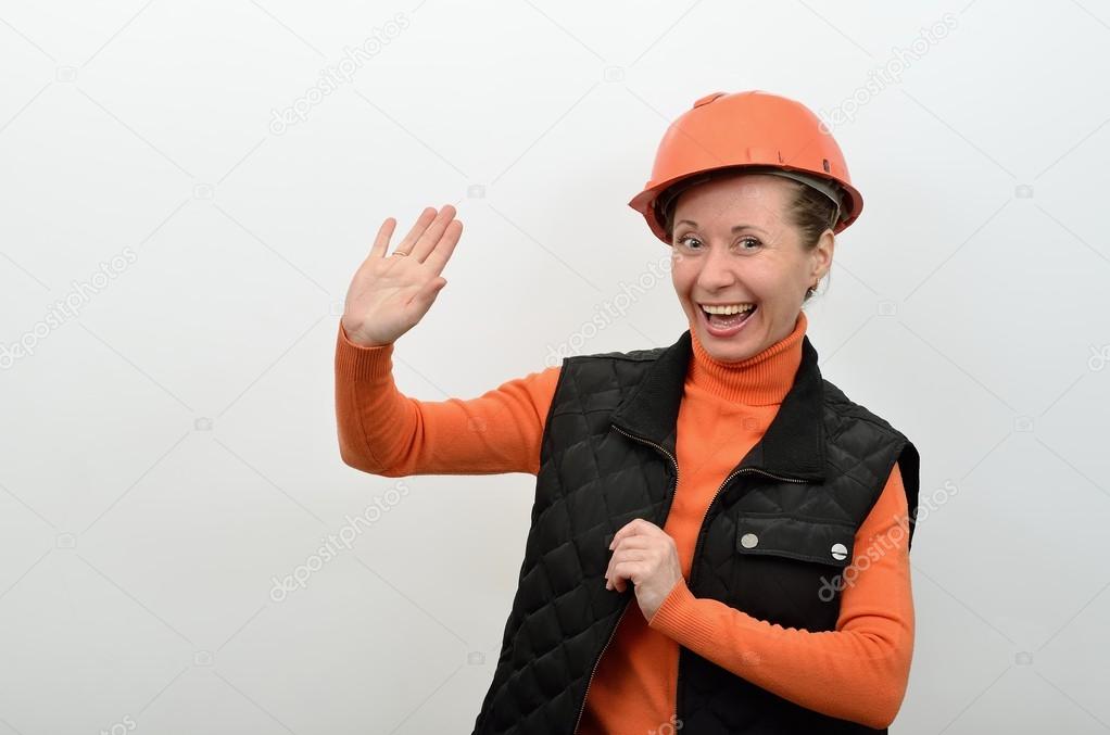 Woman builder welcomes you, holding up his hand and smiling