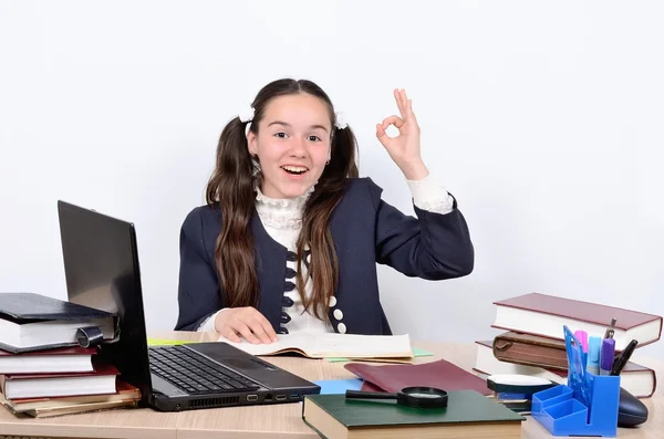 Colegiala adolescente muestra que la buena fortuna complacido sentado en un escritorio de la escuela —  Fotos de Stock