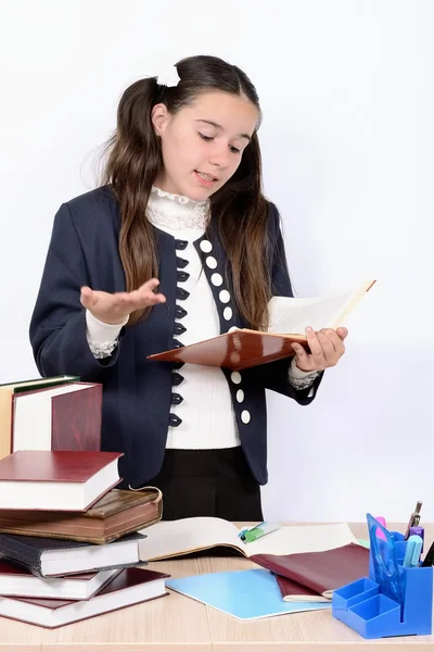 Adolescent écolière lit manuel derrière un bureau avec l 'livres — Photo